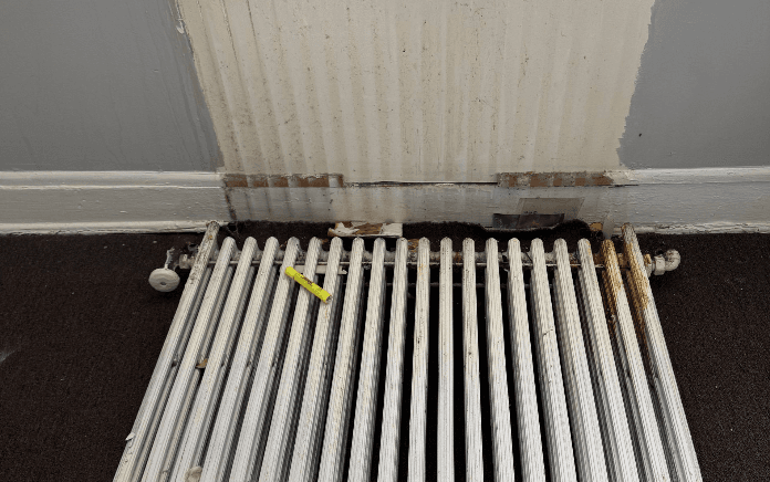 Wall damage behind radiator before repair Wall damage behind radiator before repair