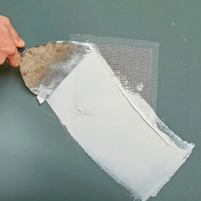 Drywall patch compound being applied over mesh for Mor Handy drywall repair Drywall patch compound being applied over mesh for Mor Handy drywall repair